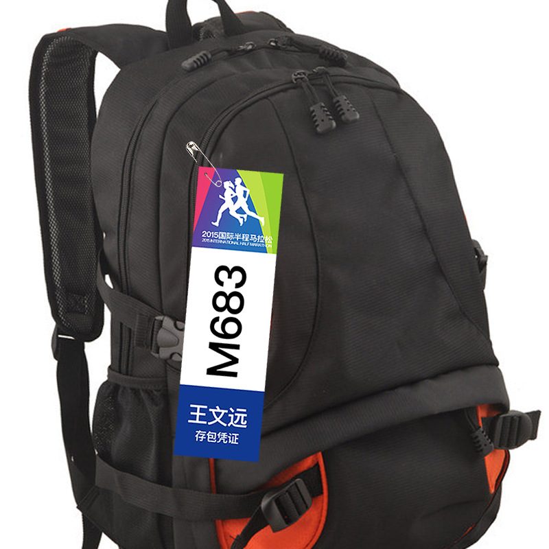 Race bib tear-off section used as a bag check voucher, pinned to a runner's bag