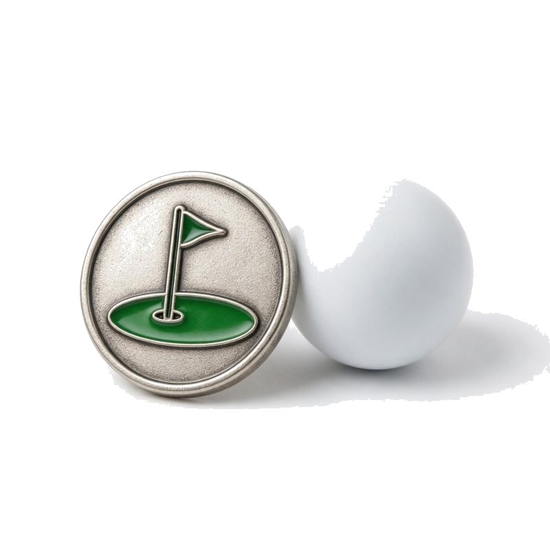 custom die-cast golf ball marker with green enamel flag inlay beside a plain white golf ball